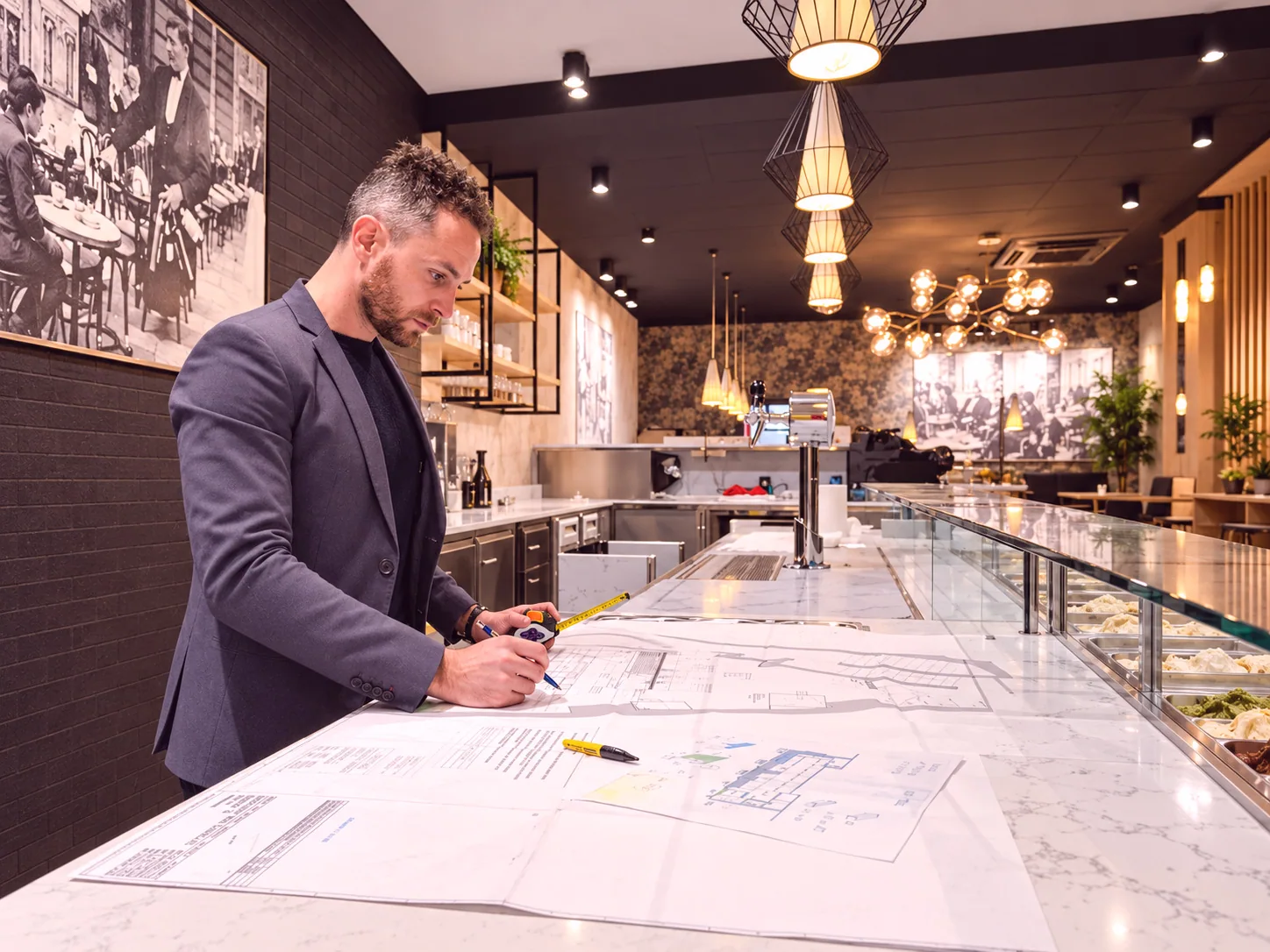 Architetto al lavoro su disegni progettuali all’interno di una gelateria